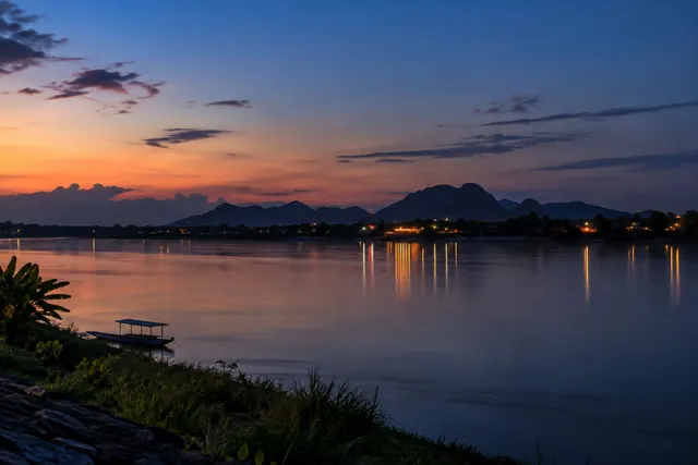 แสงเย็นและไฟหมู่บ้านสะท้อนแม่น้ำโขง สื่อถึงการพักใจเมื่อวันหนัก